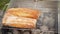 Unrecognizable person grilling fresh baguette on barbecue