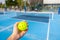 Unrecognizable person holding a plastic yellow pickleball ball