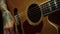 Unrecognizable person playing acoustic guitar in dark recording studio.