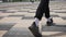 An unrecognizable person walks along the sidewalk. Male feet in sneakers and white socks.