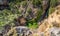 Unrecognizable persons canyoning with ropes under the water stream