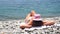 Unrecognizable positive woman in white bikini sunbathing or tanning on seaside beach during summer. Slow motion of happy