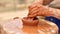 Unrecognizable pottery woman working with pottery wheel in cozy workshop creates vase or mug