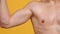 Unrecognizable shirtless sportsman flexing muscular biceps, exercising over orange background, slow motion