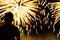 Unrecognizable silhouette of a boy with his back to us, who watches the show Fireworks. Festive background with place