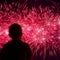 Unrecognizable silhouette of the boy`s back to us, which looks enchanting show of fireworks. Festive square background