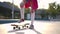 Unrecognizable slim teen girl start riding skateboard in sunbeam leaving in slow motion. Caucasian teenage skater