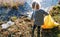 Unrecognizable small child collecting rubbish outdoors in nature, plogging concept.