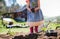 Unrecognizable small girl with strawberry plant in garden, sustainable lifestyle concept.