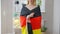 Unrecognizable smiling woman wrapping in German flag and smiling standing indoors at home. Proud Caucasian happy lady
