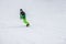 Unrecognizable snowboarder skiing in bright green suit, protective glasses mask on the slope, overalls. Winter sport