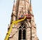 Unrecognizable team workers on tall lifting platform repairing the church facade