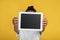 Unrecognizable teen afro american girl in white t-shirt show tablet with blank screen, isolated on yellow background