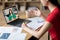 Unrecognizable teen chinese lady gestures at table with laptop with female teacher at screen in room