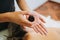 Unrecognizable therapist putting massage oil in her hand, to make a relaxing massage to a female patient.