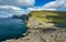 Unrecognizable tourists taking photos to the steep coast in Faroe Islands