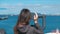 Unrecognizable woman brunette looks through binoculars at the sea.