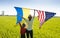 unrecognizable woman with child on sunny day stands with back and raises two large flags - American and Ukrainian