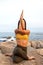 Unrecognizable woman doing gomukhasana with garudasana arms. Yoga practice in nature near the ocean. Vertical image.