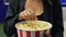 Unrecognizable woman eating popcorn at the cinema.