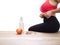 Unrecognizable woman grabbing her love handles on white background with measuring tape, an apple and a bottle of water