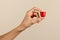 Unrecognizable woman hand showing coffee capsule against beige backdrop