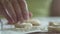 Unrecognizable woman is heaping round pieces of a dough in a flour for making dumplings, 4K close-up