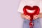 Unrecognizable woman hold in hands red inflatable foil balloon in a heart shape.