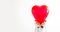unrecognizable woman holding heart shaped ballon in front of his head, against white background in white sweater. Happy valentines