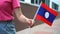 Unrecognizable woman holding Laotian flag. Girl walking down street with national flag of Laos