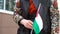 Unrecognizable woman holding Palestinian flag. Girl walking down street with national flag of Palestine