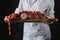 Unrecognizable woman holds cutting board with assortment of sausages