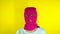Unrecognizable woman in pink balaclava sending blowing kisses on yellow background. Unknown female in mask looking at