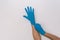 Unrecognizable woman putting on blue latex gloves