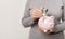 Unrecognizable woman putting cash into piggy bank