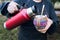 unrecognizable woman serving mate with a red thermo, in a colorful ethnic mate.