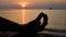 Unrecognizable woman sits in lotus position on sunset and calm sea water surface background