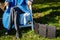 An unrecognizable woman sits in nature on green grass near a portable solar battery