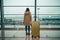 Unrecognizable woman with suitcase standing at the airport, Generative AI