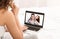 Unrecognizable woman video chatting with friends online while relaxing in bed