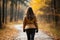 Unrecognizable woman walking in autumn forest on nature path surrounded by vibrant woods