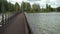 Unrecognizable woman walking with bicycle on long wooden bridge over lake