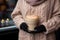 Unrecognizable woman in warm knitted sweater and gloves holding a big cup of coffee latte outdoors