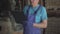 Unrecognizable worker in blue uniform and working gloves writing in documents standing in warehouse. Male Caucasian