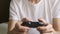 Unrecognizable young adult playing videogames, holding controller in hands