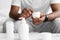 Unrecognizable young african american guy in white clothes hold jar of cream, cosmetic on table, indoor