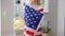 Unrecognizable young American woman wrapping in US flag smiling. Happy positive proud lady posing at home indoors with