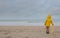 Unrecognizable young boy with bright yellow oilskin jacket on a deserted beach