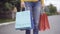 Unrecognizable young Caucasian woman standing with shopping bags outdoors. Legs of slim stylish female shopper with