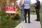 Unrecognizable young couple with real estate agent looking at residential property for sale, outside